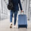 Unrecognizable Man With Bag And Suitcase Walking In Airport Terminal, Rear View Of Young Male On His Way To Flight Boarding Gate, Ready For Business Travel Or Vacation Journey, Cropped, Copy Space