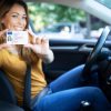 driver license Driving school. Young beautiful woman successfully passed driving school test. Female smiling and holding driver's license. Girl with driving license.